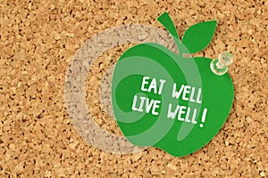 Eat well, Live well! written on apple shaped paper note on pinboard