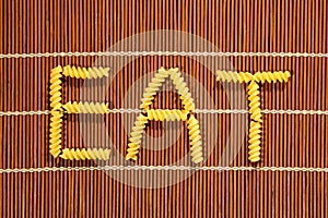 EAT word made with raw pasta elements on bamboo set