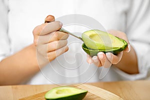 Eating Avocado. Woman Hands Peeling Fresh Avocado With Spoon