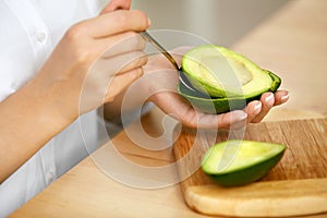 Eating Avocado. Woman Hands Peeling Fresh Avocado With Spoon