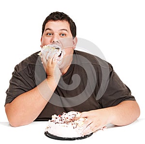 Eating cake in record time. An obese young man stuffing a cake down his face and not being too dainty about it.