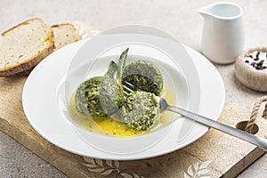 Eating canederli with spinach served with melted butter and sage.