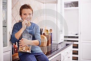 Eating, cookies and portrait of child in home with glass, container or happy with jar of sweets on kitchen counter