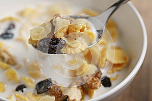 Eating corn flakes with fruits and nuts in white bowl