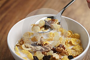 Eating corn flakes with fruits and nuts in white bowl