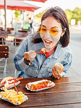 Eating Currywurst fast food German sausage in outdoor street food cafe