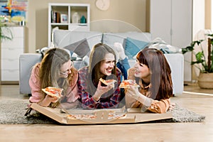 Eating Fast Food. Happy three Beautiful Friends Laughing, Eating Pizza At Home Party. Women Having Dinner Together