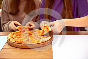 Eating Food in cafe. Closeup People Hands Taking Slices Of Pepperoni Pizza. Two girl Friends Sharing Pizza Together