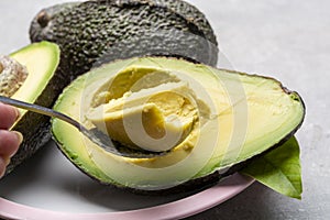 Eating of fresh ripe green organic hass avocado fruit with spoon photo