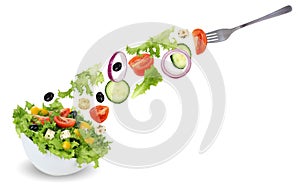 Eating green salad in bowl with fork, tomatoes, onion, olives an