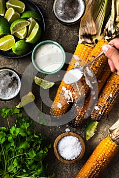 Eating grilled corn cobs with fresh herbs,lime,beer and salsa