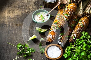 Eating grilled corn cobs with fresh herbs,lime,beer and salsa