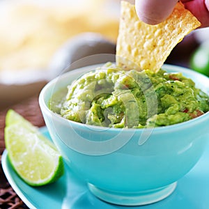 Eating guacamole with tortilla chip from bowl photo