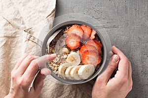 Eating healthy breakfast bowl. Muesli and fresh fruits in ceramic bowl in woman` s hands. Clean eating, dieting, detox, vegetaria