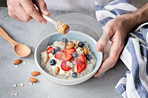 Eating healthy breakfast oatmeal porridge with fresh berries and nuts