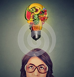 Eating healthy idea concept. woman looking up light bulb made of fruits above head