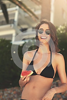 Eating healthy pays off in summer. a young woman enjoying a slice of watermelon on the beach.