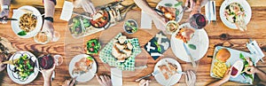 Eating and leisure concept - group of people having dinner at table with food