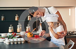 Eating pepper. Mother with her daughter are preparing food on the kitchen