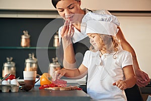 Eating pepper. Mother with her daughter are preparing food on the kitchen