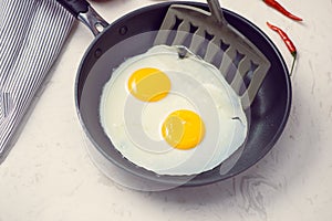 Eating in the process, fried eggs in a frying pan for breakfast