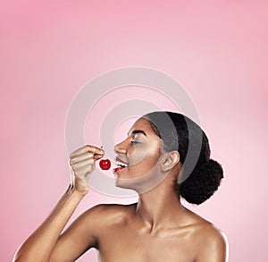 Eating, profile and black woman with cherry for nutrition, health and healthy diet isolated on pink background. Skin
