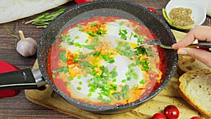 Eating shakshuka, tomato eggs. hands cutting poached eggs in tomatoes with fork, spicy shakshouka, slow motion 4k video