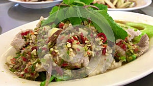 Eating spicy pork salad with spoon and fork