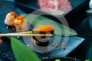 Eating Su Sushi roll japanese food in restaurant. with salmon, vegetables, flying fish roe and caviar closeup.