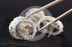 Eating Sushi with chopsticks. Sushi roll japanese food in restaurant. California Sushi roll set with salmon, vegetables, flying