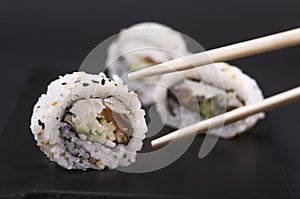 Eating Sushi with chopsticks. Sushi roll japanese food in restaurant. California Sushi roll set with salmon, vegetables, flying