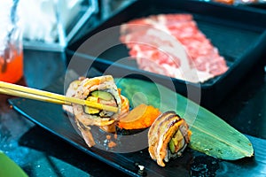 Eating Sushi with chopsticks. Sushi roll japanese food in restaurant. with salmon, vegetables, flying fish roe and caviar closeup.