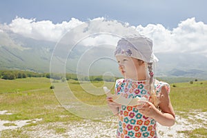 Eating sweet melon slice little girl enjoying Alpine view