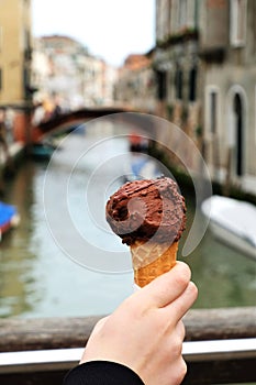 Eating traditional italina ice-cream gelato on a bridge over canal in Venice, Italy