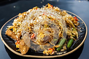 eating udon noodles with pork and colorful vegetables on black background. Asian cuisine. Street food concept.