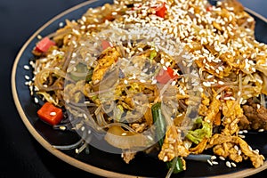 eating udon noodles with pork and colorful vegetables on black background. Asian cuisine. Street food concept.