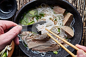 Eating vietnamese pho with chopsticks and spoon