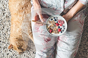 Eating yogurt with granola and berries. Female eating healthy breakfast