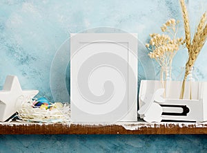 Eatser mock up with photoframe, painted eggs in nest and white wooden bunny on shelf against blue wall. Scandinavian style home de