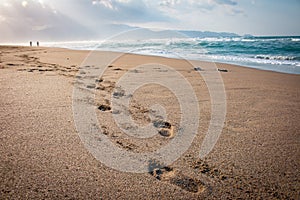 Eautiful beach with footprints in the sand. Couple of lovers walking on the beach at sunset and leaving foot prints on the beach.