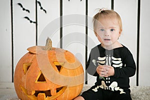 eautiful little girl with Down syndrome sitting near a pumpkin on Halloween dressed as a skeleton