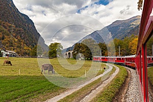Eautiful view of red Rhaetian train running towards Brusio spiral viaduct, Grisons, Switzerland