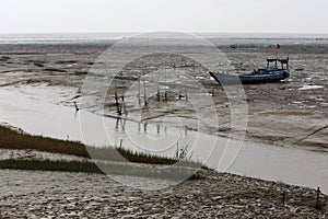 After the ebb, the boat ran aground on the tidal flat river of mud, photo
