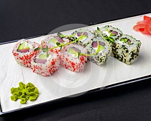 Ebiko black caviar adn red caviar sushi rolls - japanese food style. Served on a white plate over black background