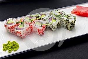 Ebiko black caviar adn red caviar sushi rolls - japanese food style. Served on a white plate over black background