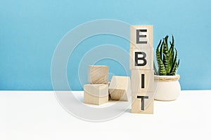 ebit - word is written on wooden cubes on a blue background. close-up of wooden elements. in the background is a green