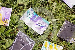 Ebru painting by colorful paints. Bright abstract patterns on paper sheets on green grass.