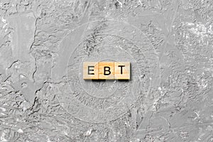 EBT word written on wood block. Abbreviation Earnings Before Taxes text on cement table for your desing, concept