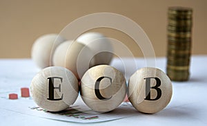 ECB - abbreviation on wooden balls on a background of coins and graphics photo