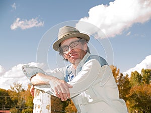 Eccentric man leaning to a fence post